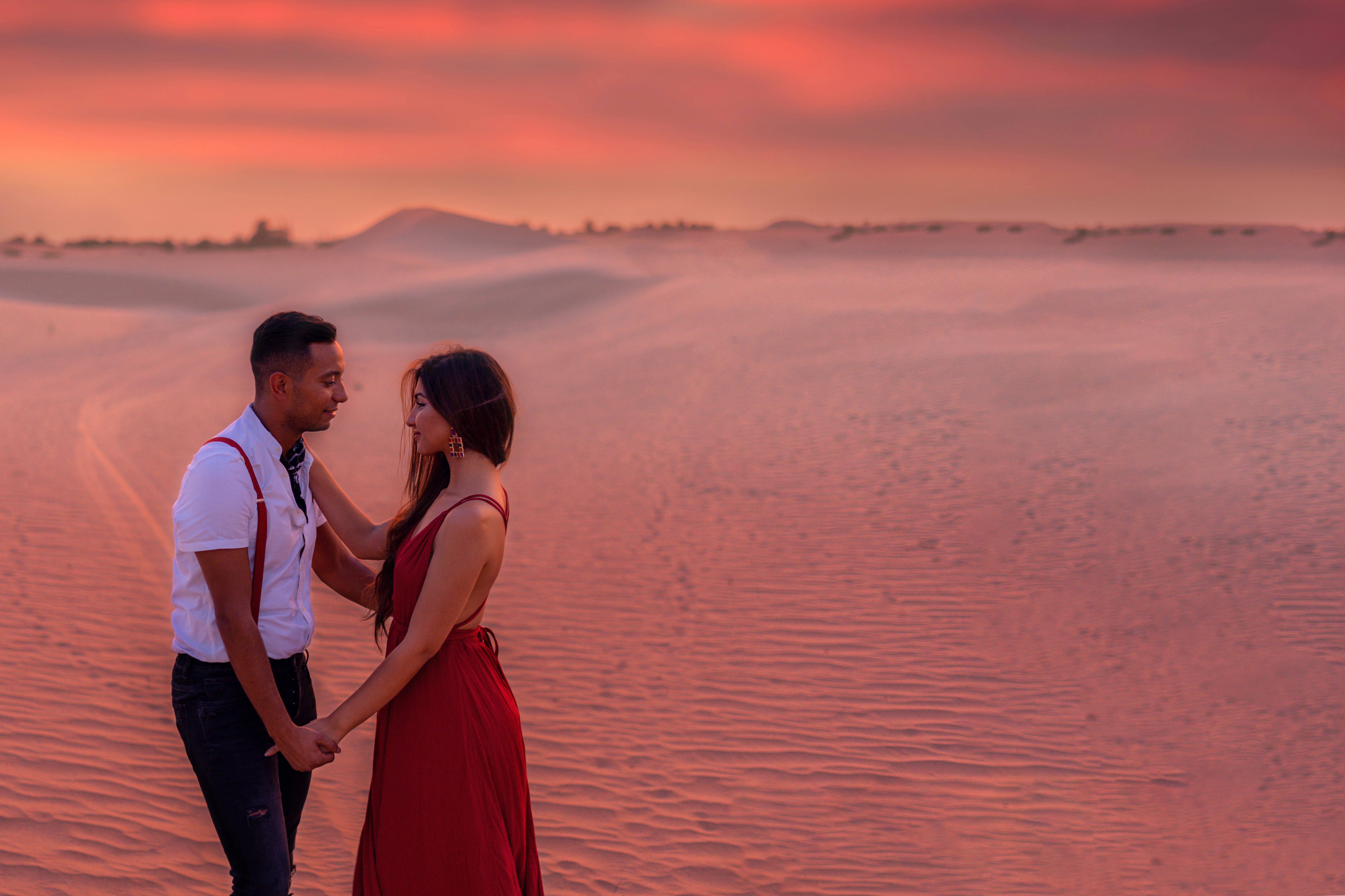 man and woman standing on seashore during sunset